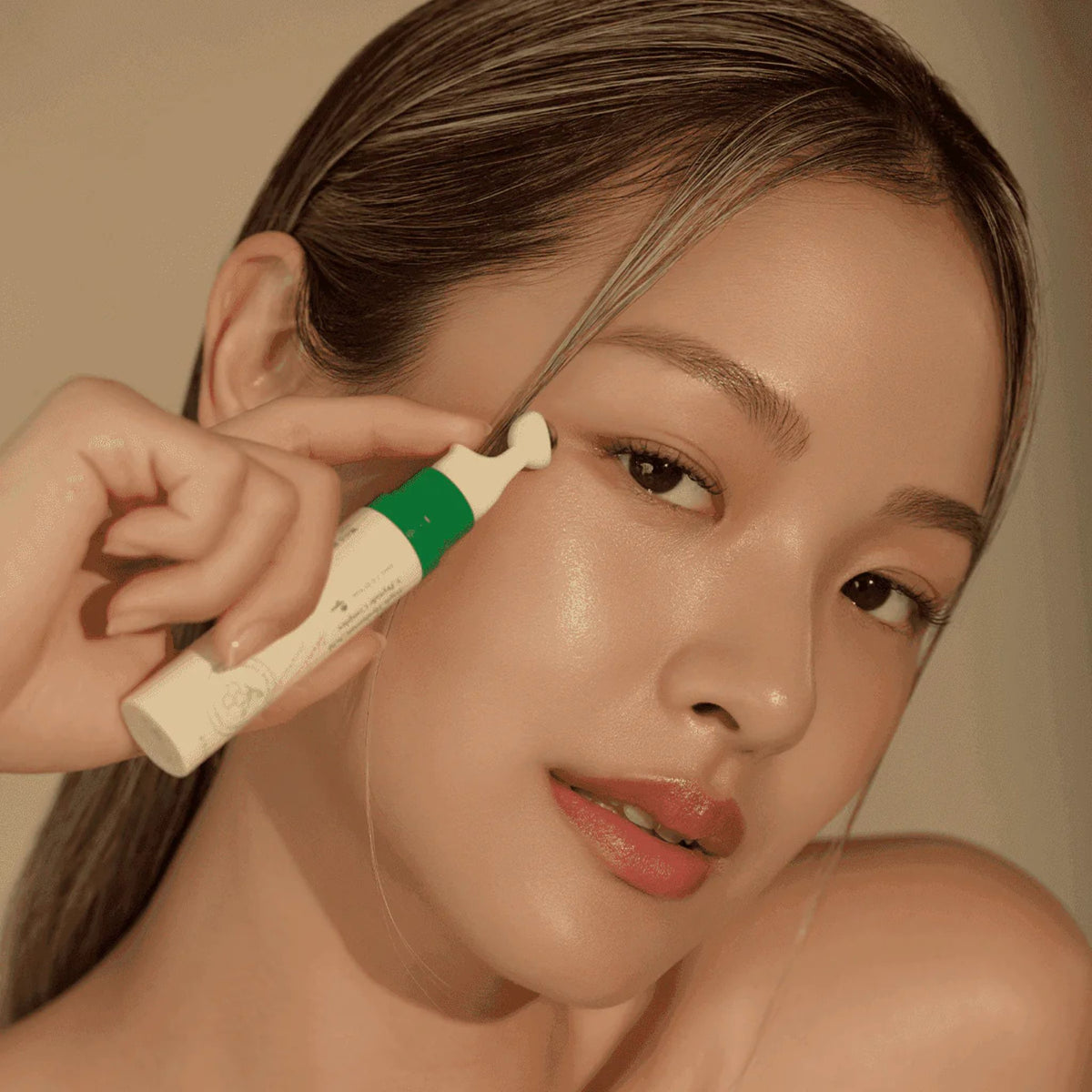 Model applying AXIS-Y Vegan Collagen Eye Serum under eyes using cooling metal applicator for de-puffing and firming effect