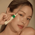 Model applying AXIS-Y Vegan Collagen Eye Serum under eyes using cooling metal applicator for de-puffing and firming effect