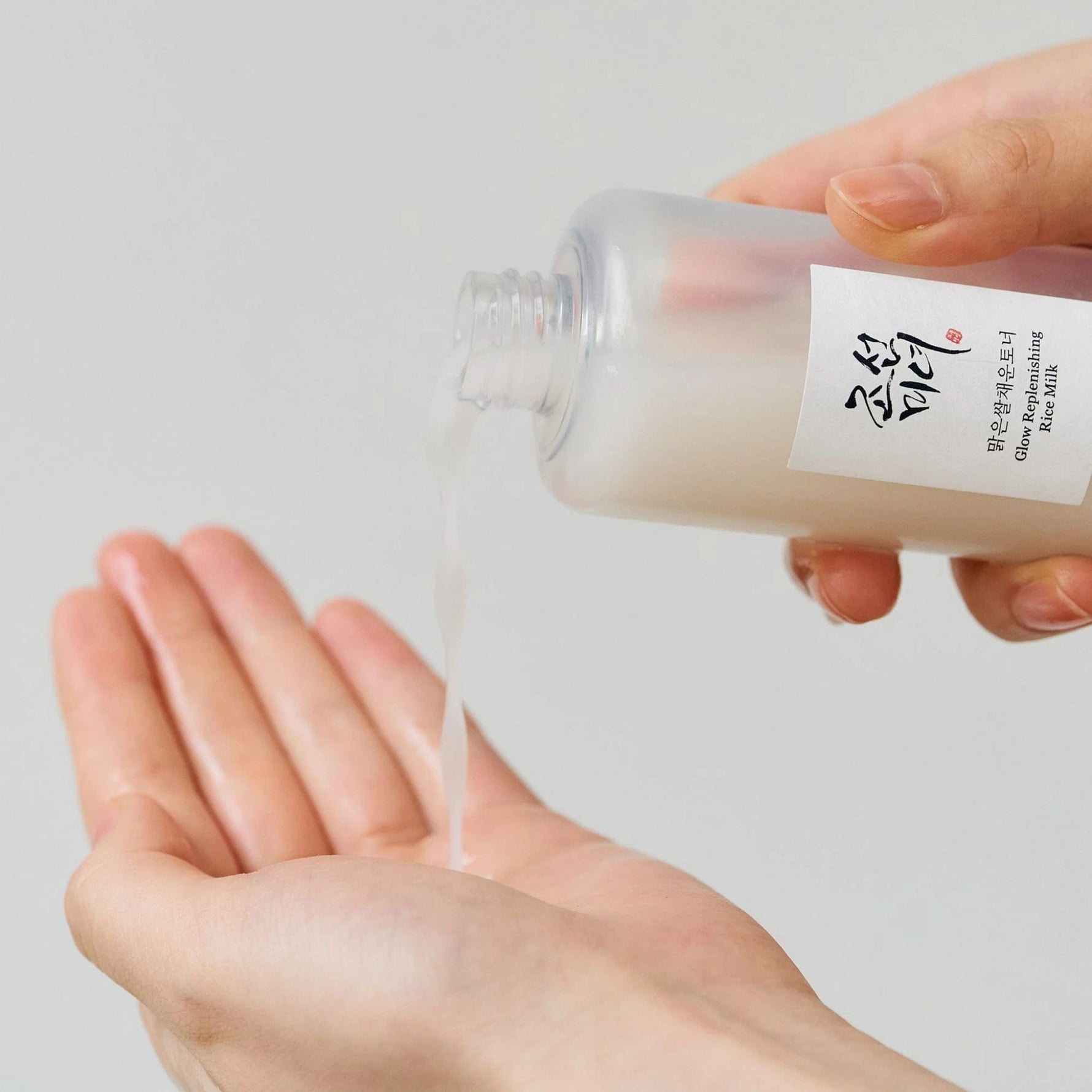 Beauty of Joseon Glow Replenishing Rice Milk Toner being poured into hand, nourishing Korean toner with rice extract for hydration and radiance.