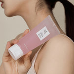 Model holding Beauty of Joseon Red Bean Water Gel pink tube against shoulder for skincare routine