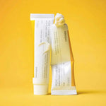 Two Celimax Pore + Dark Spot Brightening Cream tubes on yellow background with creamy white texture swirl - tranexamic acid and niacinamide cream