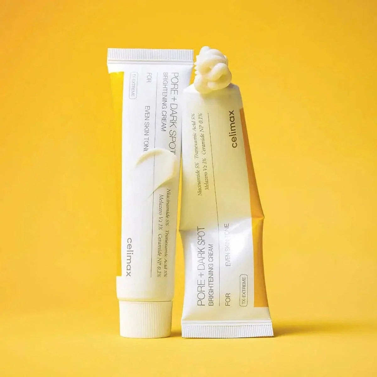 Two Celimax Pore + Dark Spot Brightening Cream tubes on yellow background with creamy white texture swirl - tranexamic acid and niacinamide cream