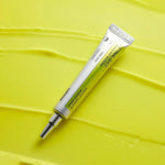 Celimax Retinal Shot Tightening Booster tube resting on smooth yellow cream texture - Korean anti-aging retinal booster