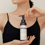 Model holding Klairs Gentle Black Deep Cleansing Oil — a lightweight vegan cleansing oil that removes makeup and impurities gently