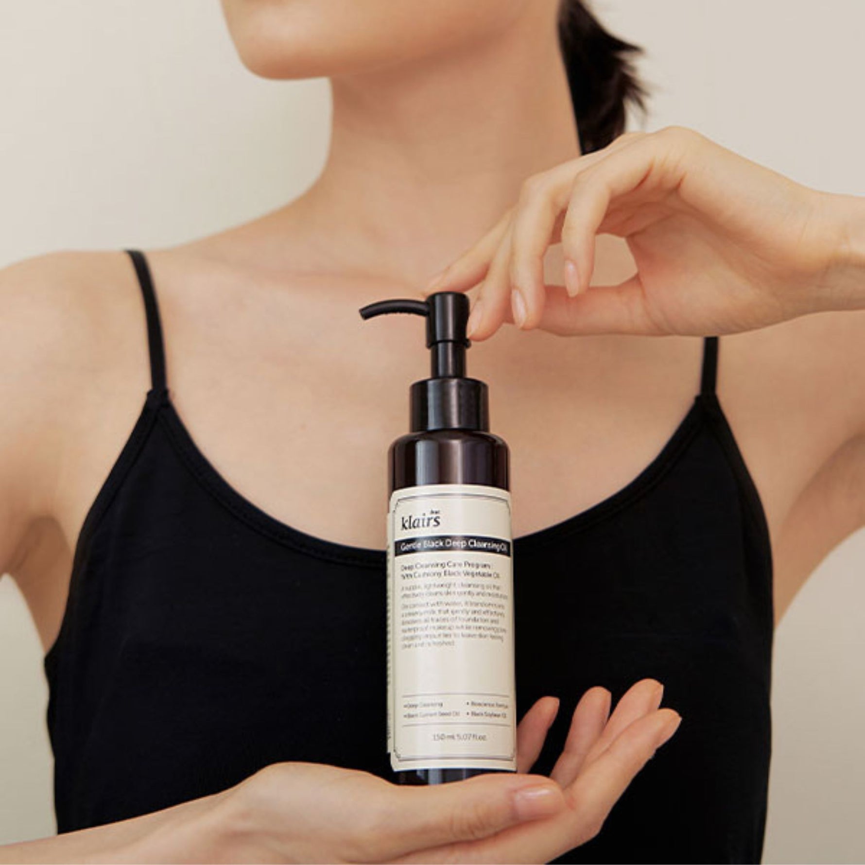 Model holding Klairs Gentle Black Deep Cleansing Oil — a lightweight vegan cleansing oil that removes makeup and impurities gently