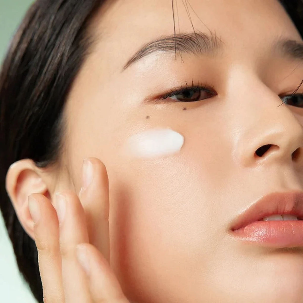 Woman applying Korean eye cream under the eye – firming under-eye care for dark circles and fine lines