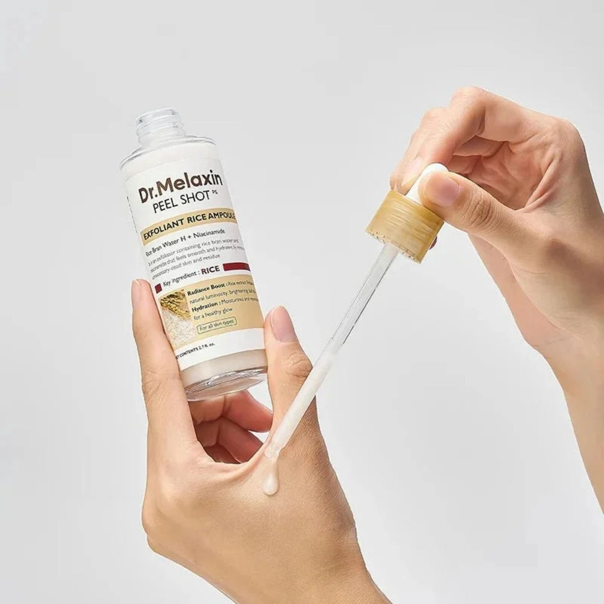 Applying Dr.Melaxin Peel Shot Rice Ampoule from the dropper onto the hand – milky exfoliating serum texture