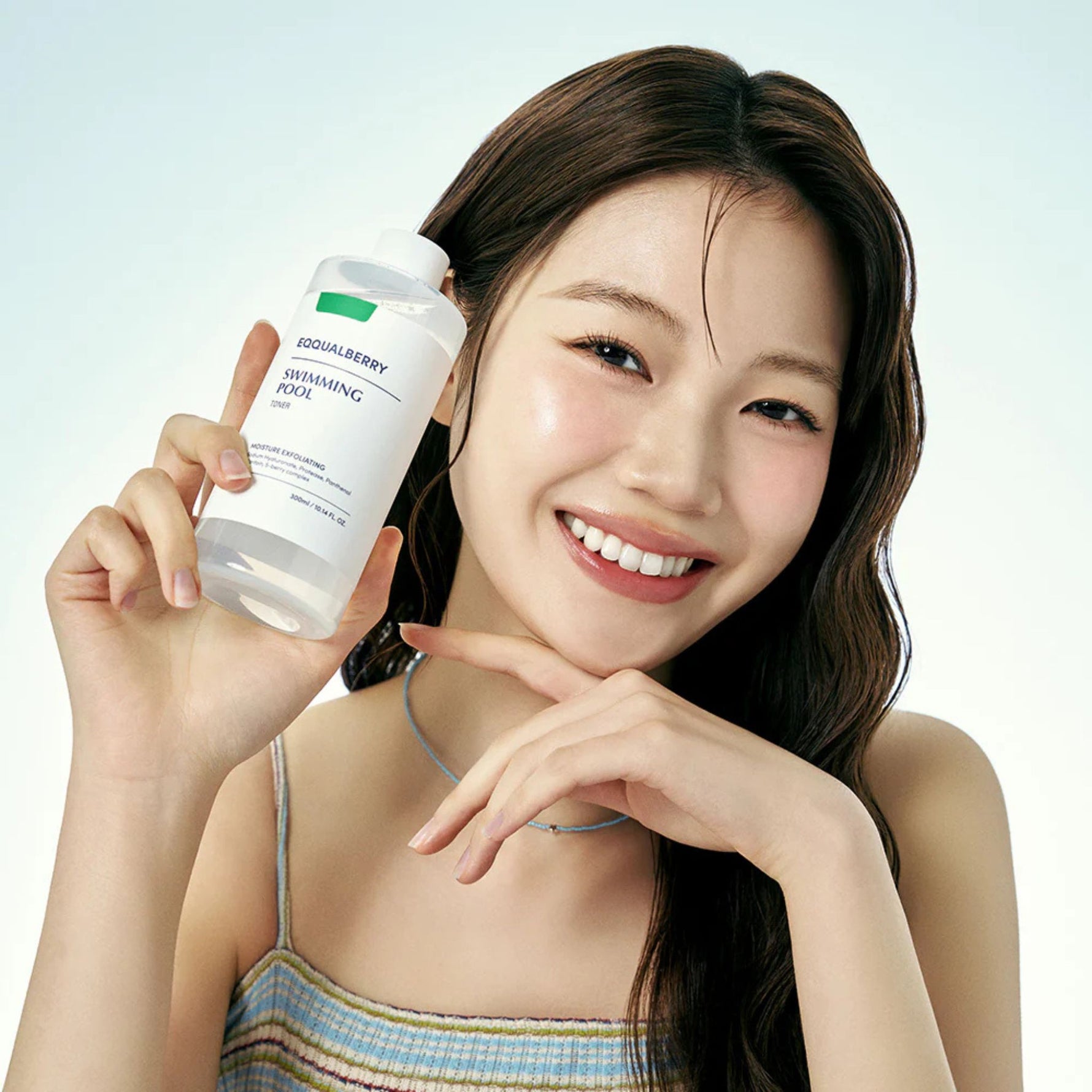 Smiling model holding Eqqualberry Swimming Pool Toner 300ml, Korean hydrating exfoliating toner for daily skincare routine