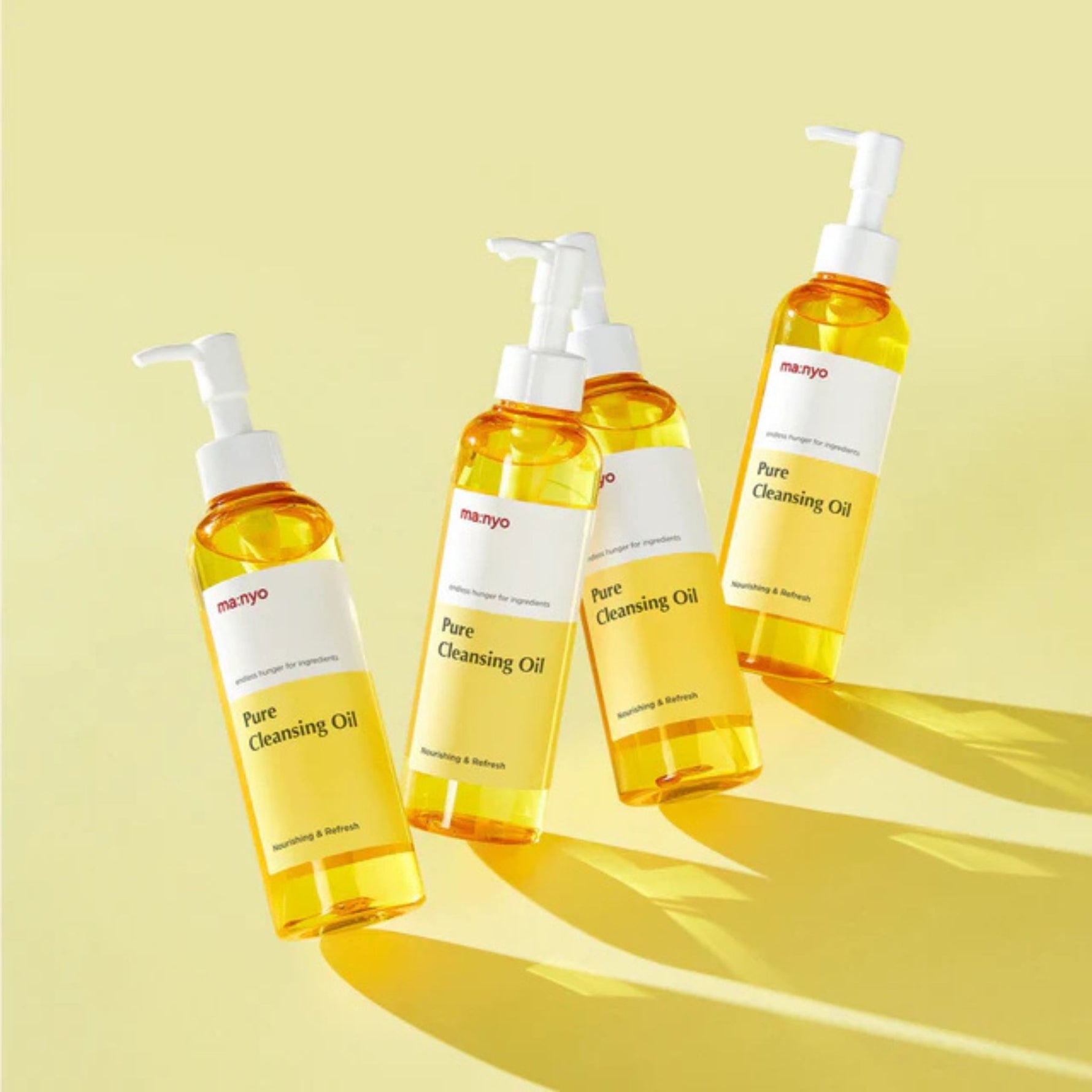 Flat lay of four Manyo Pure Cleansing Oil bottles on yellow background – bright and refreshing Korean skincare cleanser lineup