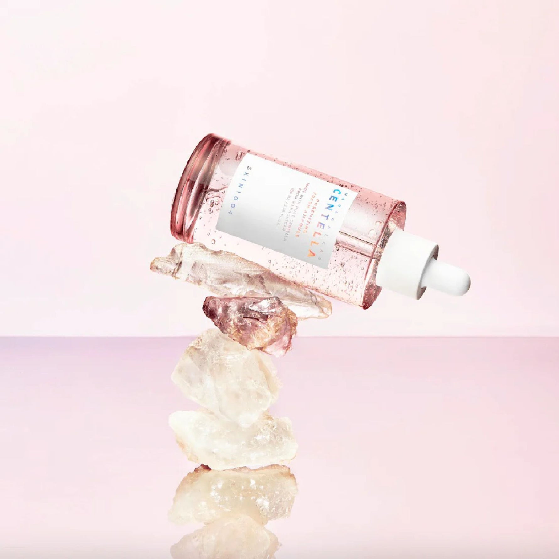 Skin1004 Madagascar Centella Poremizing Fresh Ampoule balancing on rose quartz crystals luxury skincare product shot