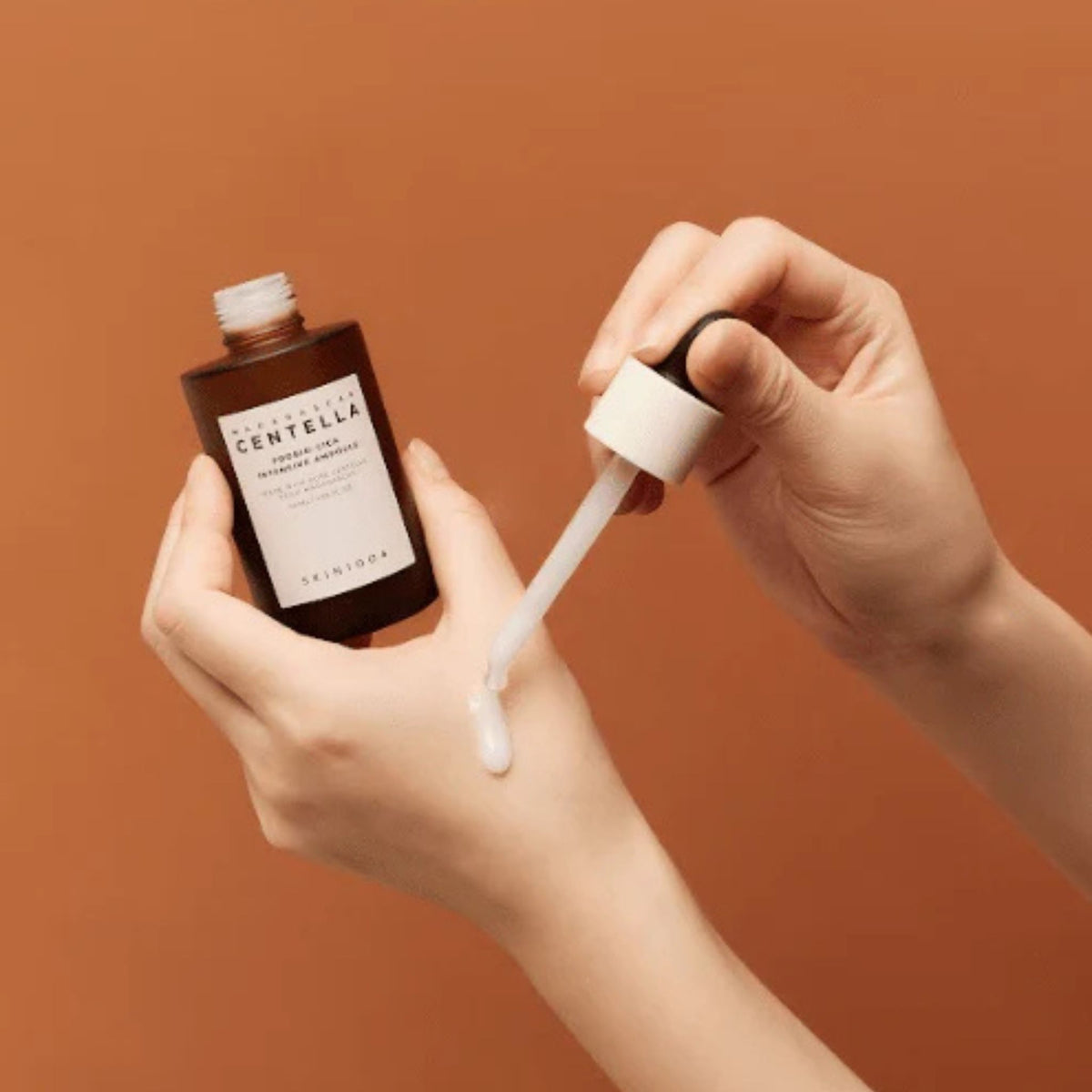 Skin1004 Madagascar Centella Probio-Cica Intensive Ampoule with dropper applying serum on hand – soothing and repairing face ampoule for sensitive skin