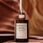 Close-up of Skin1004 Madagascar Centella Probio-Cica Intensive Ampoule with dropper releasing serum – probiotic and centella hydrating ampoule